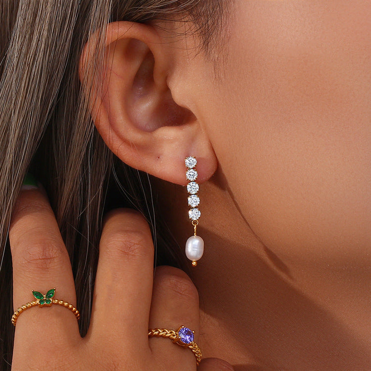 picture closer to woman's ear with her showing off a pearl and diamond earring and moving her hair out of the way