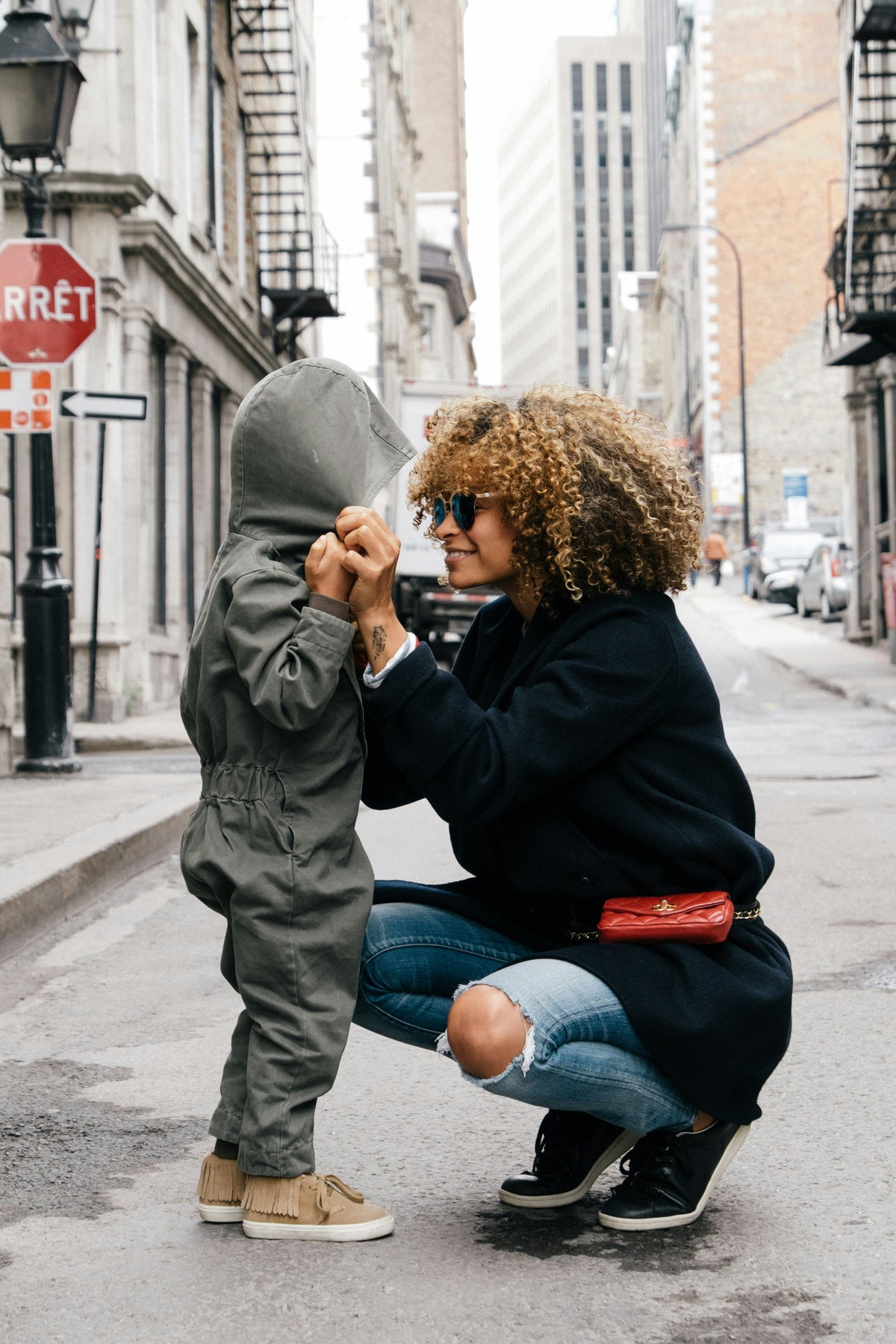 Woman bending down holding onto her toddler hands smiling 