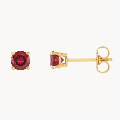 Gold earrings with red gemstones on a white background