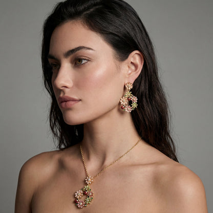 Woman wearing a gold necklace and earrings against a gray background
