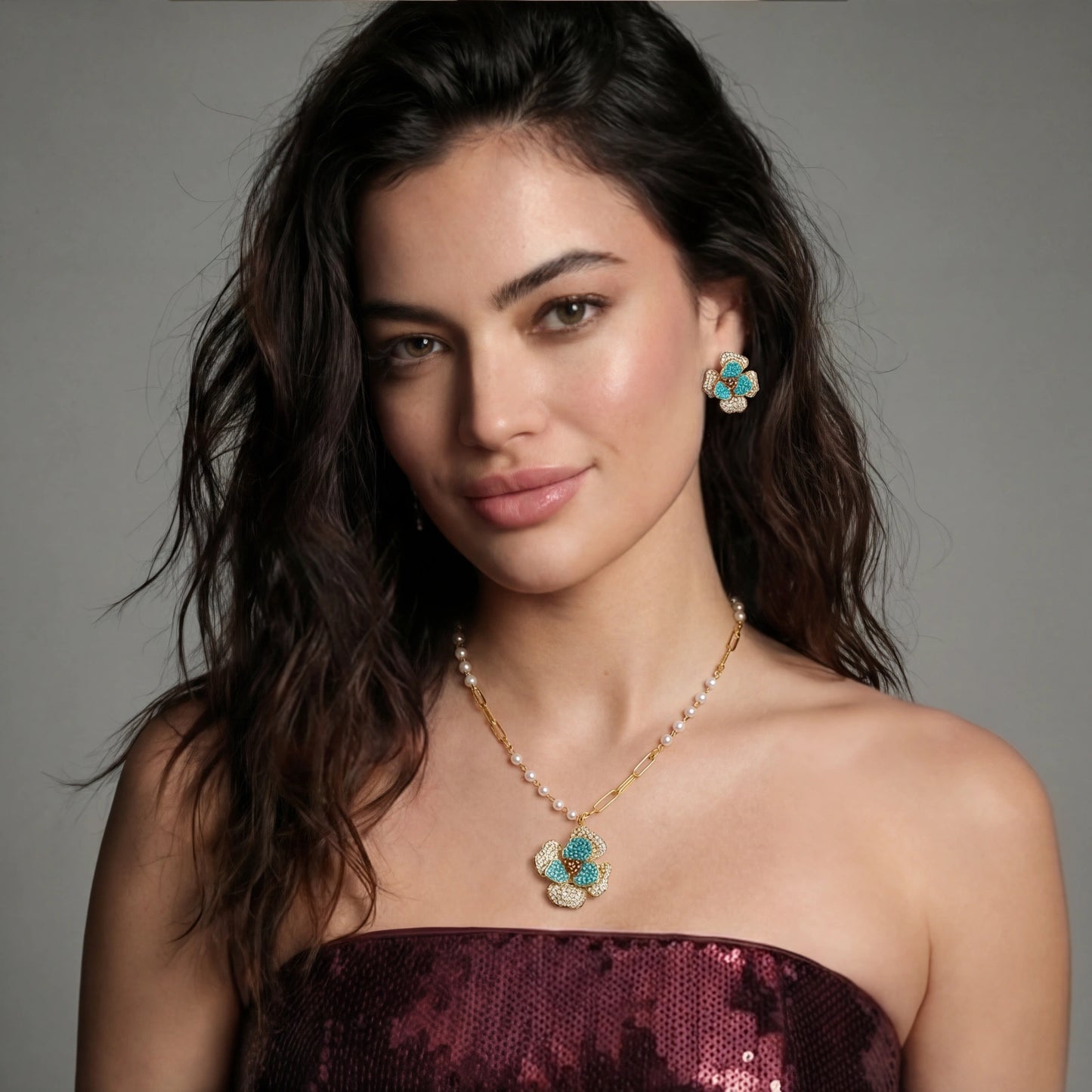 Woman wearing a necklace and earrings against a gray background