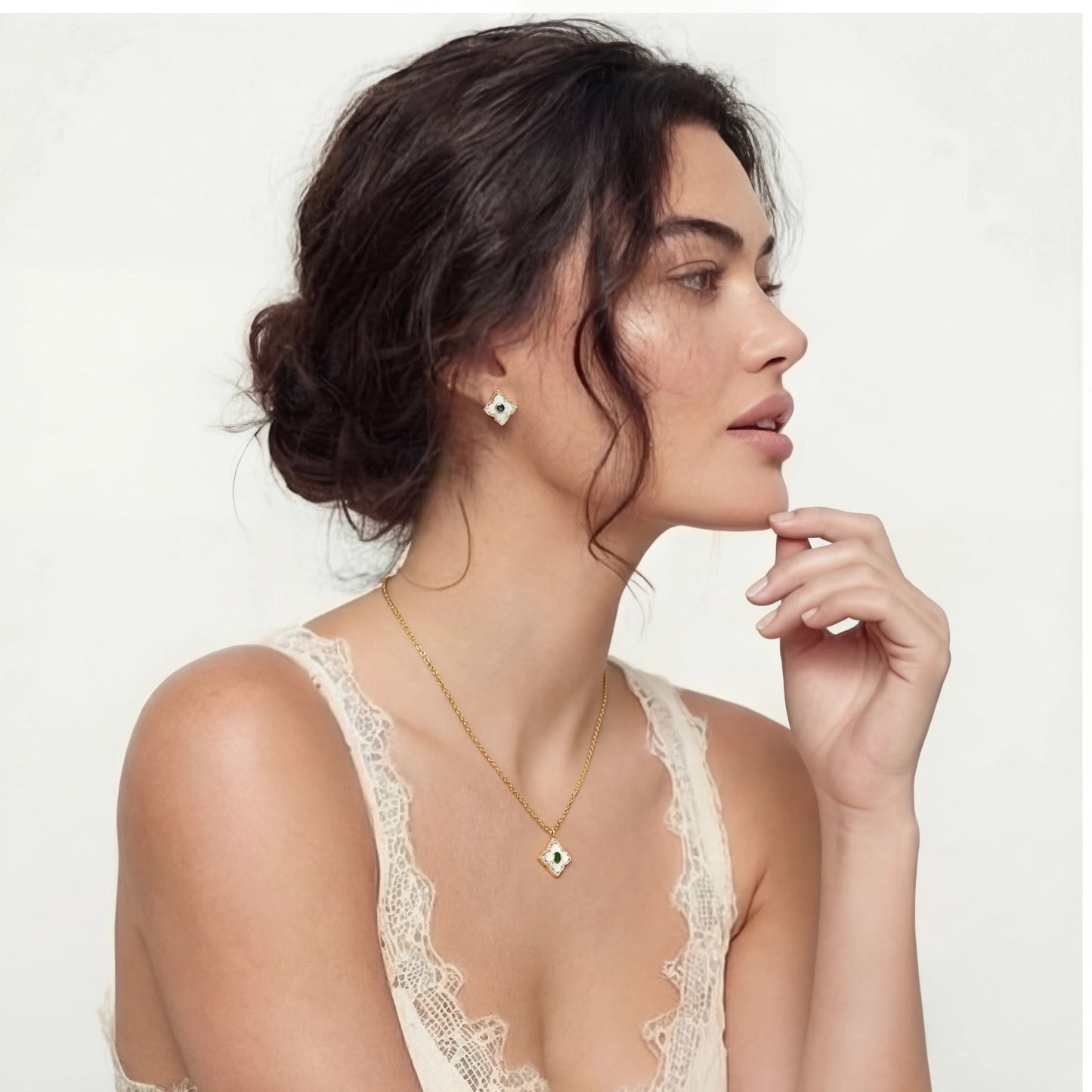 Woman wearing a gold necklace and earrings on a plain background