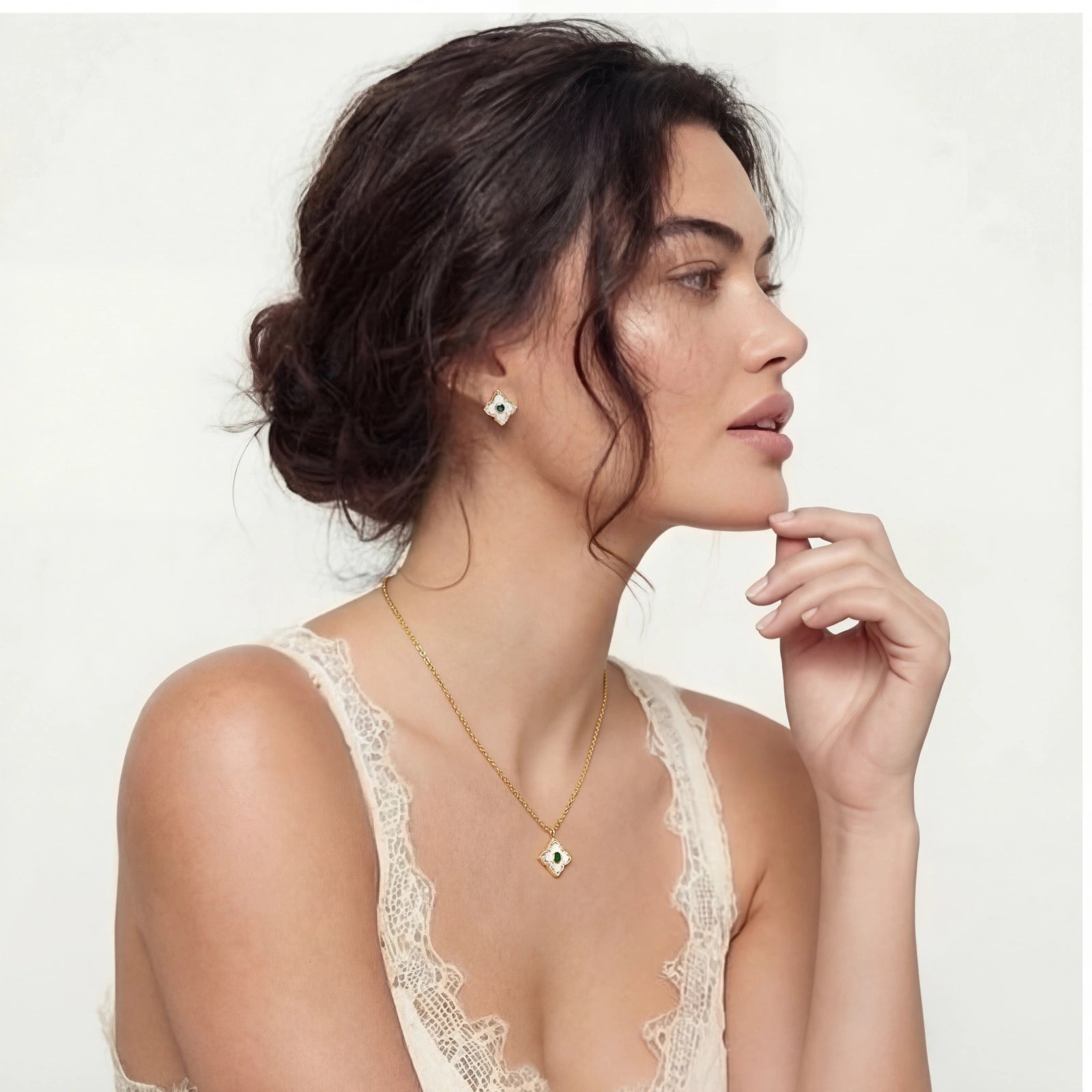 Woman wearing a gold necklace and earrings on a plain background