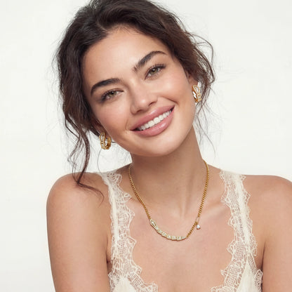 Woman wearing gold jewelry including earrings and a necklace on a white background