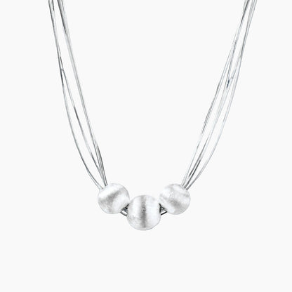 Sterling silver multi-strand necklace with three brushed round beads on cream background