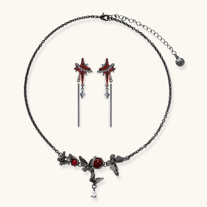 Gothic jewelry set with red resin cross pendants wrapped in dark metal chains on cream background.