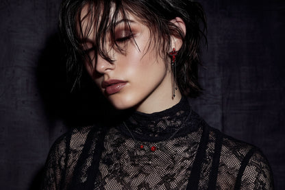 Close-up of a person wearing a black lace top with red embellishments against a dark background.