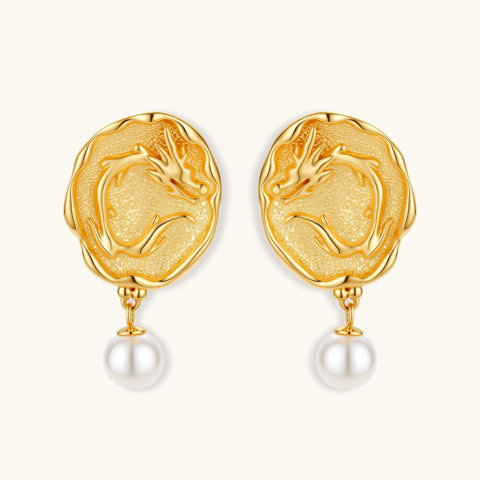 Ornate gold-plated dragon medallion earrings with white shell pearl drops on beige background, featuring detailed Chinese motifs.