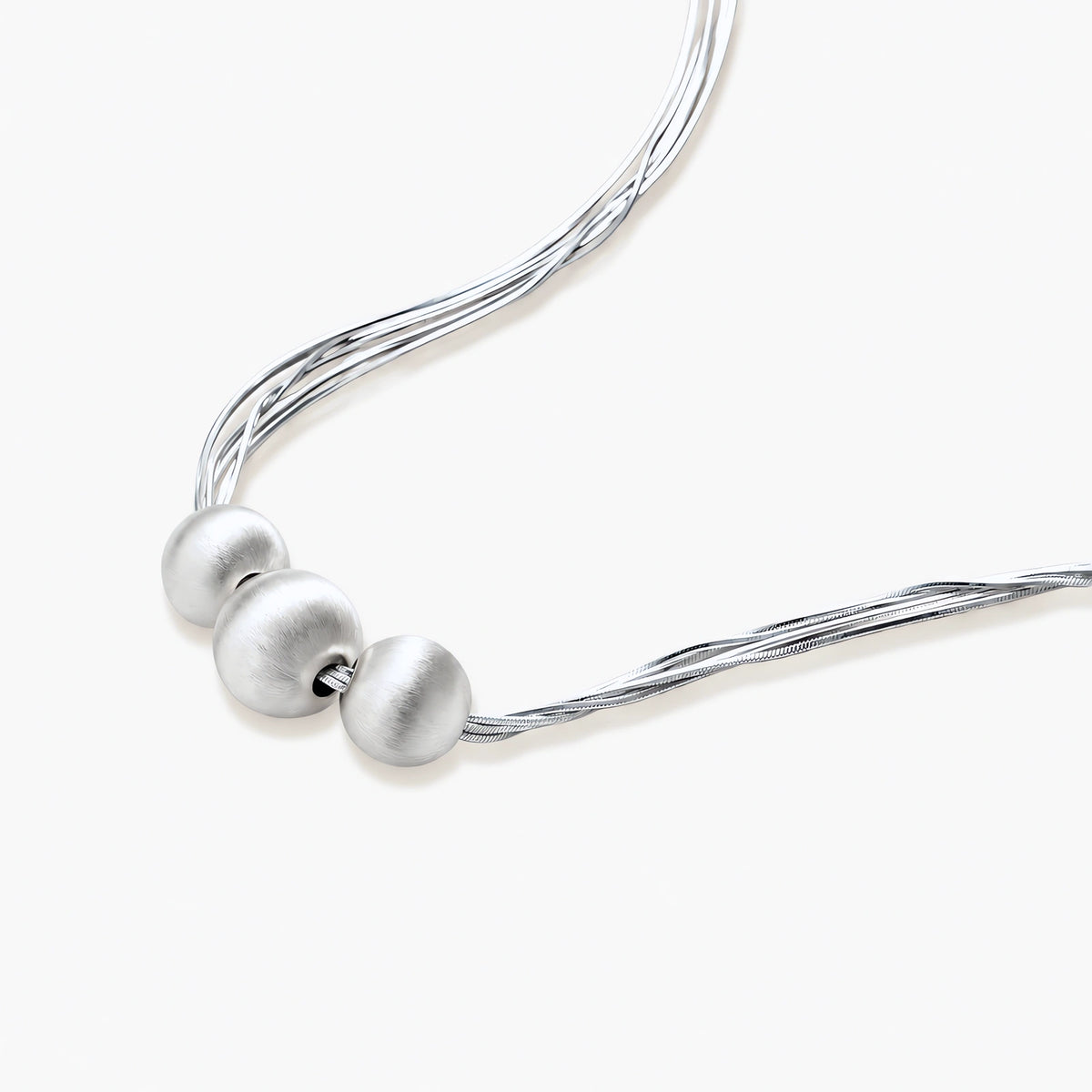 Sterling silver multi-strand necklace with three brushed round beads on cream background