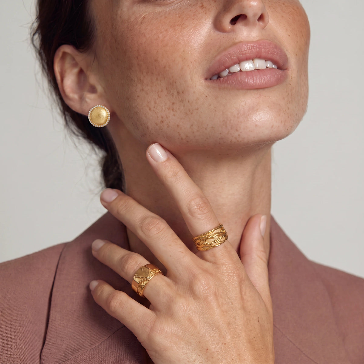 Pair of round dome stud earrings in brushed 18K gold-plated silver with a sparkling CZ halo border, push-back closure.