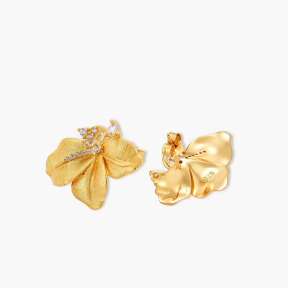 Gold-plated 925 silver flower stud earrings with brushed finish, swirl detail, and pavé cubic zirconia on cream background.