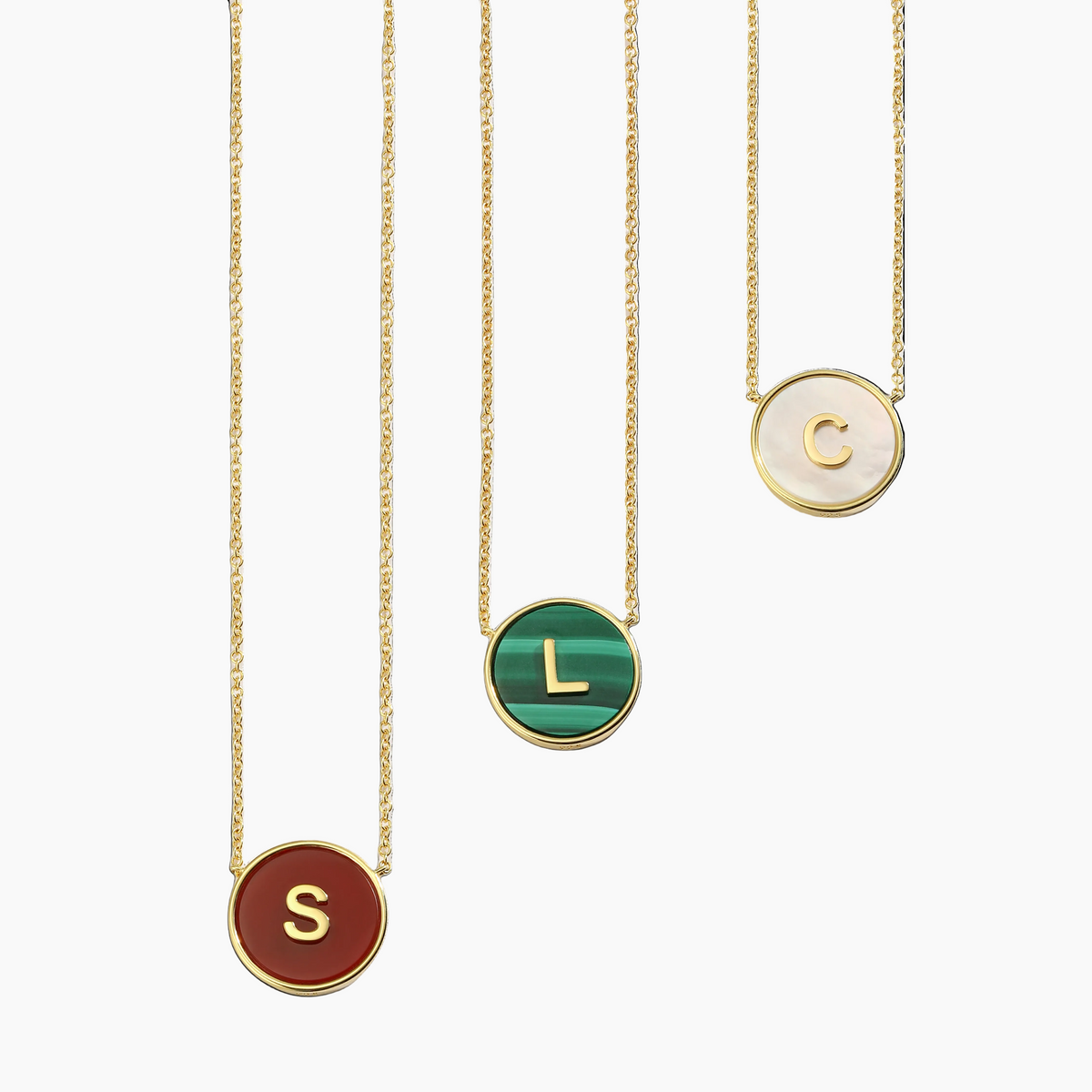 Three 18K gold plated necklaces with round pendants displaying custom letters on a white background