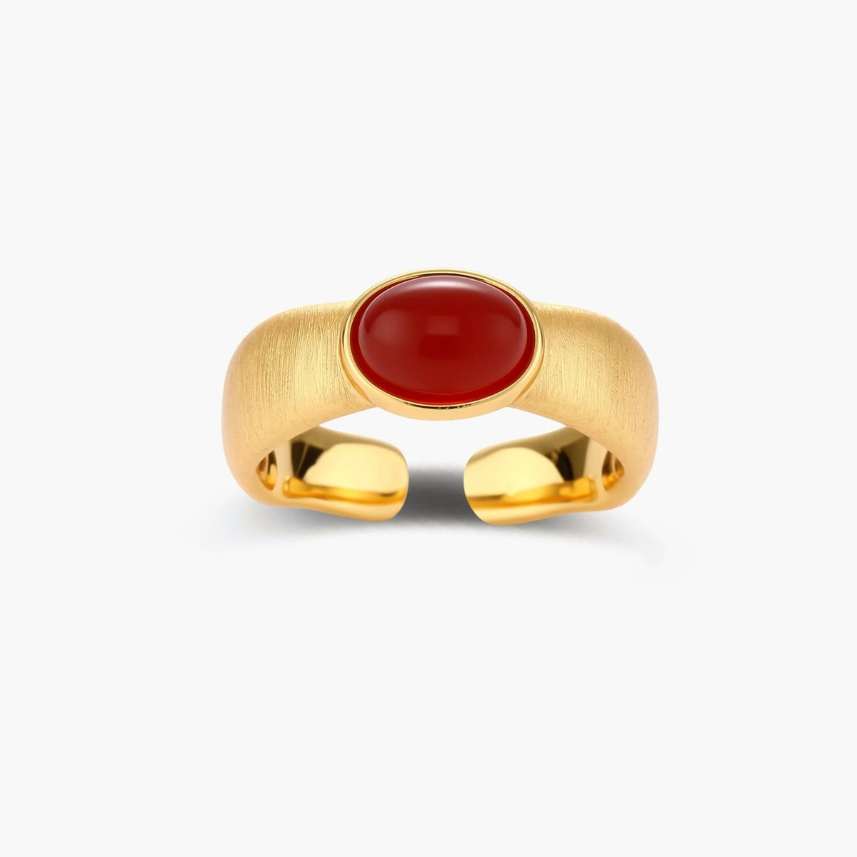 Close-up of brushed gold-plated ring with deep red oval stone, featuring adjustable band design on neutral background.