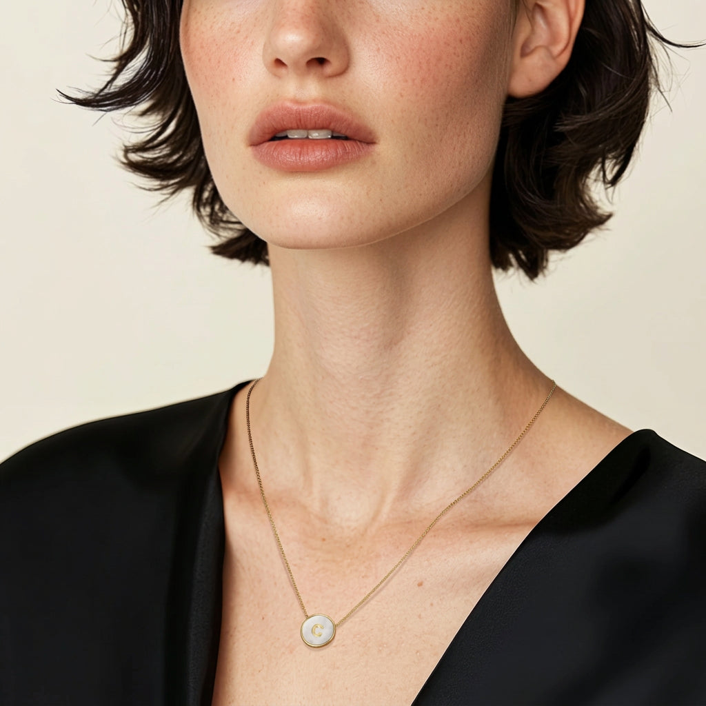 A woman wearing the custom letter pendant on her neck with a neutral background color 