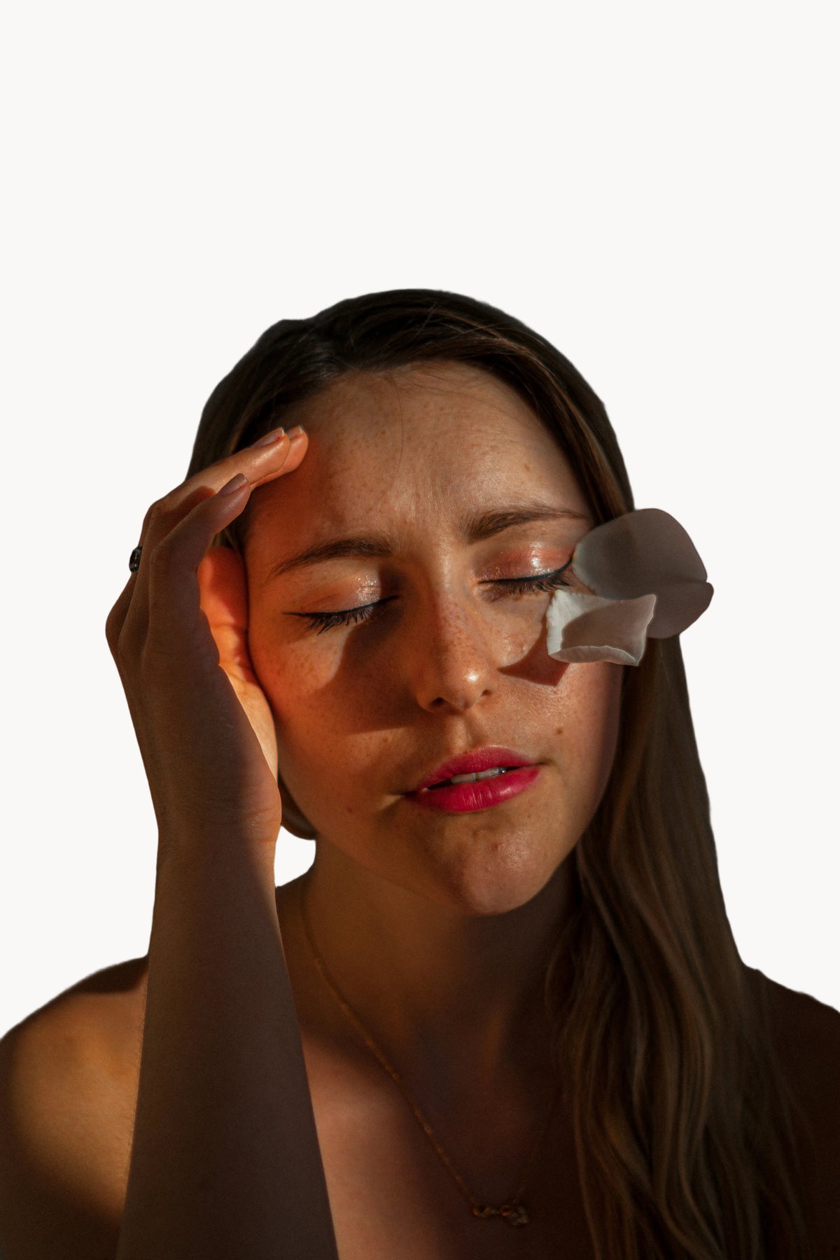 Woman applying a patch to her face against a dark background